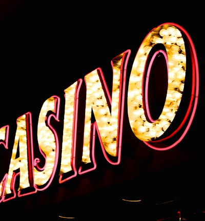 Brightly illuminated letters spell out 'CASINO' with glowing yellow bulbs and red outlines against a dark background.